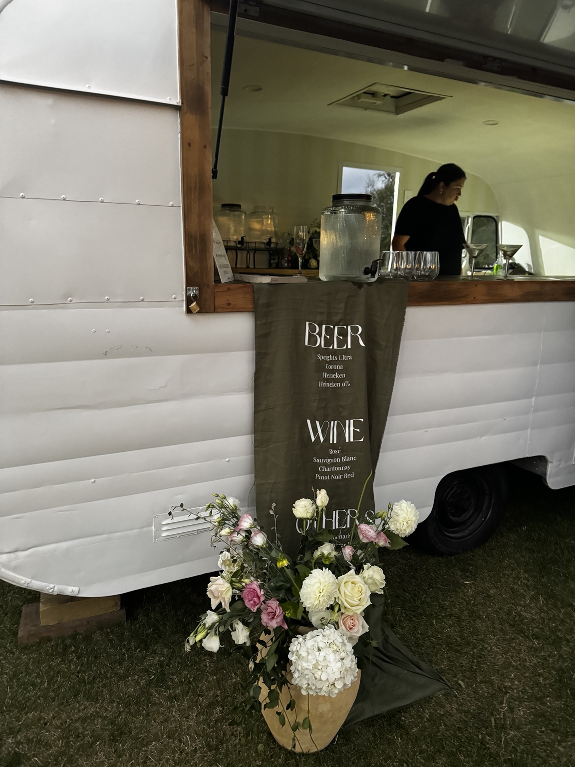 Fabric drinks menu and floral styling beside the caravan